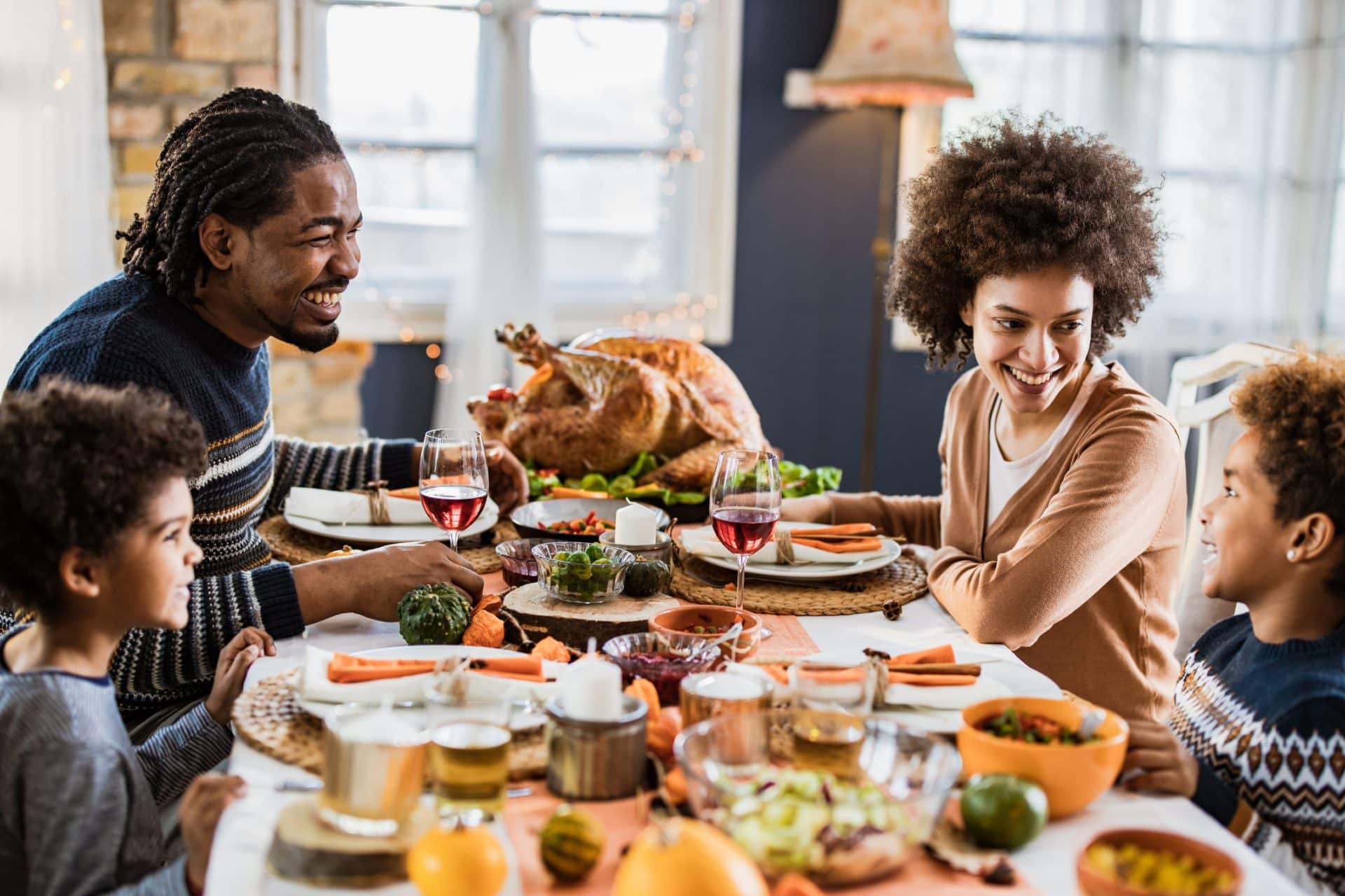 Happy family communicating while having Thanksgiving lunch in dining room.