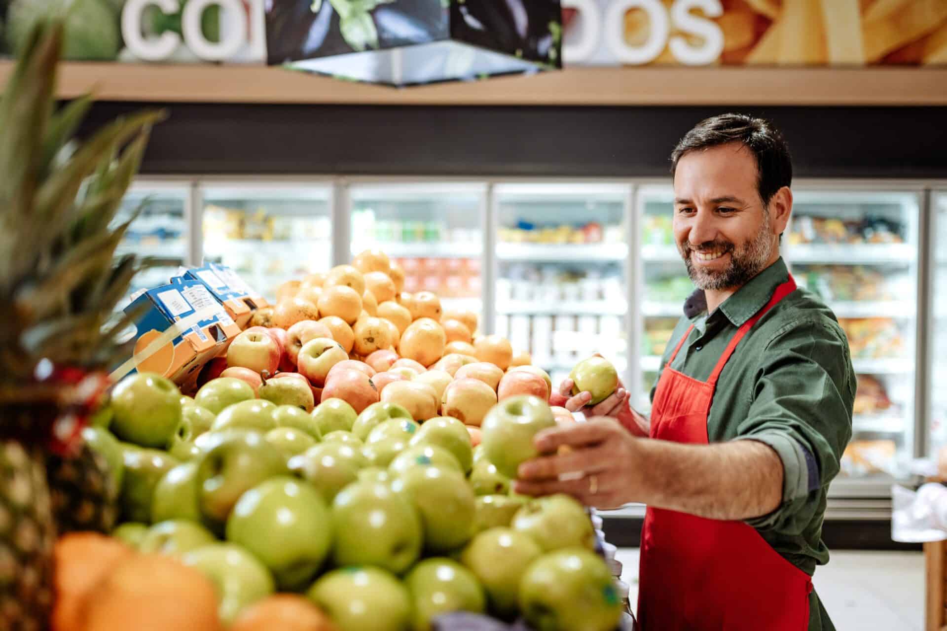 Employee in supermarket arranging fruit stack