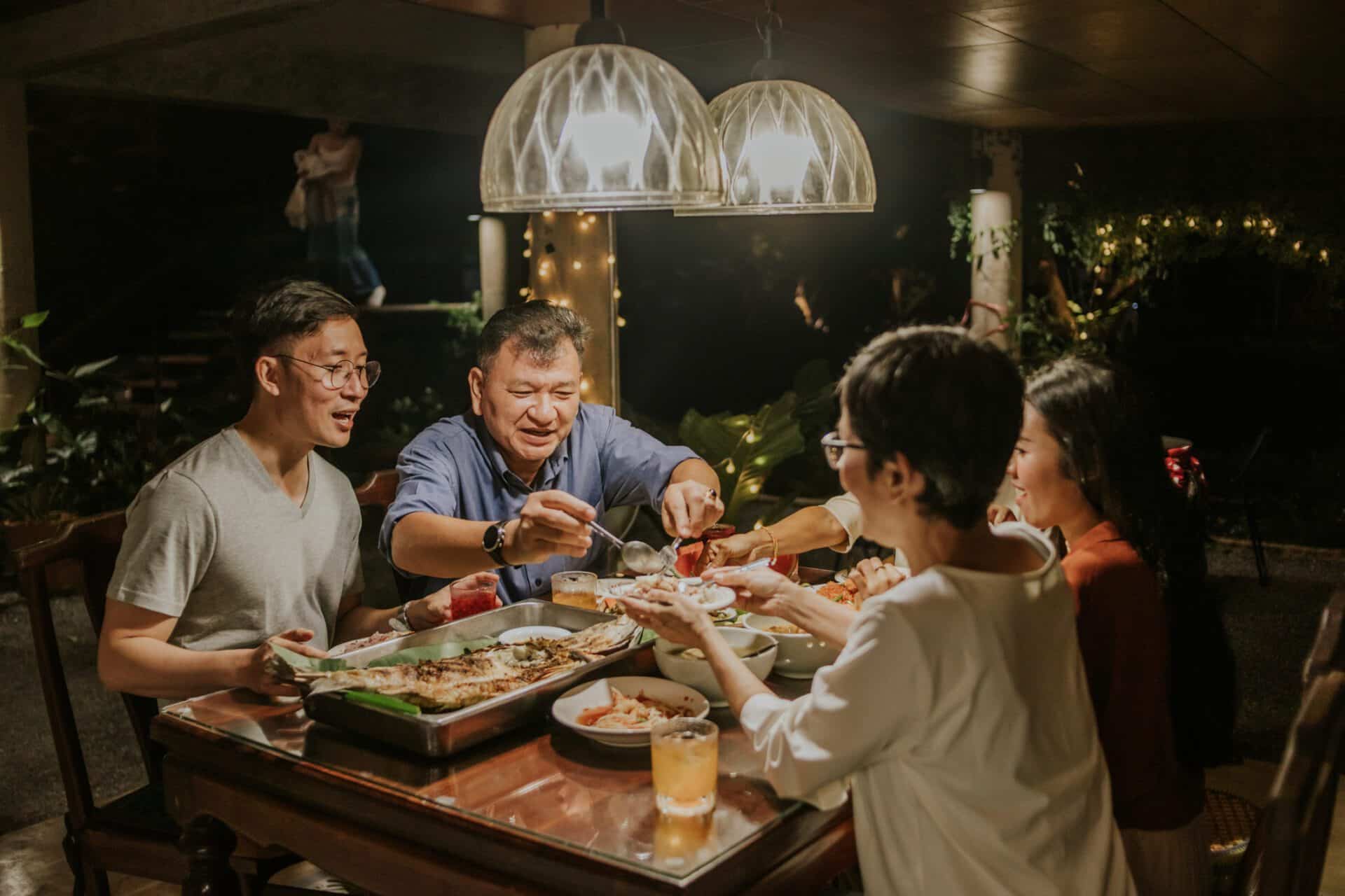 Kind father giving some food to mother with dinner party at local home town