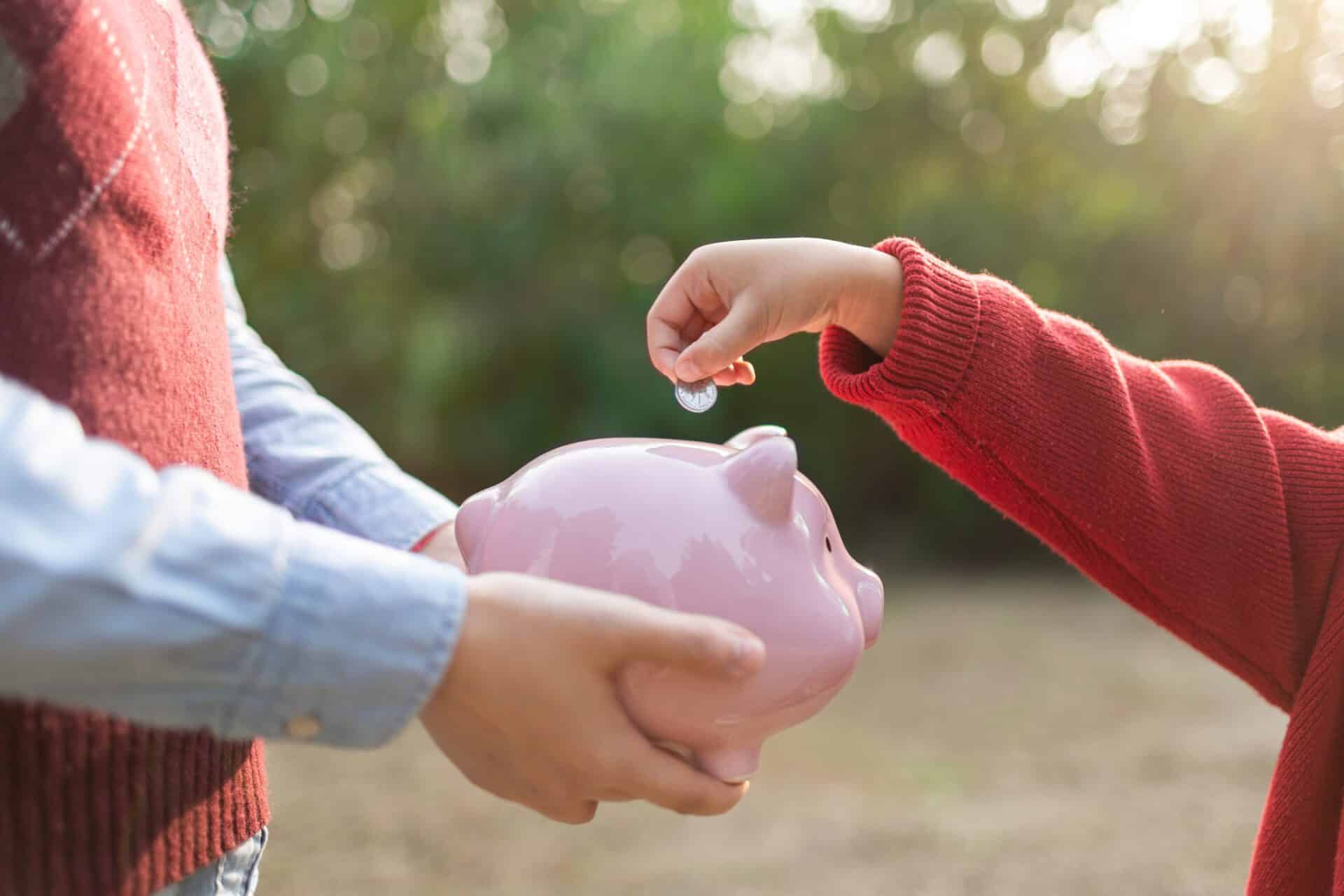 Child puts coins in the piggy bank