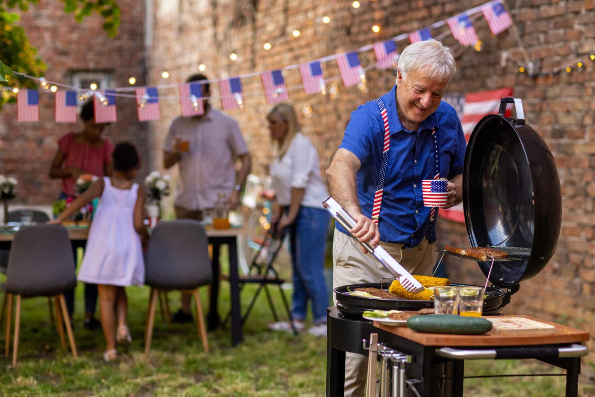 Senior man preparing barbeque for American national holiday in a backyard